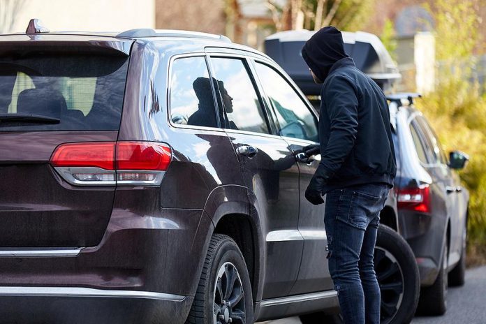 A thief trying the door of a parked vehicle