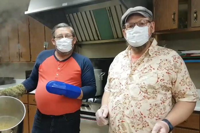 Ken Pierce and Rolf Joss of Feed The Need Havelock in a Facebook video encouraging others to do something nice for somebody as they prepare free meals at Havelock Lions Club. The two men have been preparing the meals every weekend in April and, with the help of volunteers, delivering them to people in need in Havelock, Norwood, and Campbellford. (Screenshot)