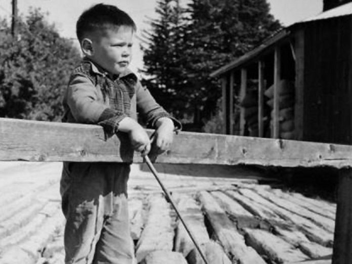 Five-year-old Neil Young in August 1950, fishing from a wooden bridge over the Pigeon River in Omemee. In August 1951, Young contracted polio and almost lost his life. (Photo: Harold Whyte)