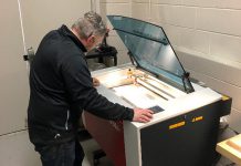 Joel Kightley, a technology teacher at St. Mary Catholic Secondary School in Cobourg, uses a laser cutter to produce pieces of a protective face shield. The technology departments at St. Mary and St. Stephen Catholic Secondary School in Bowmanville have come together to to create a manufacturing project capable of producing as many as 500 protective face shields for local health care workers. (Photo courtesy of Peterborough Victoria Northumberland and Clarington Catholic District School Board)