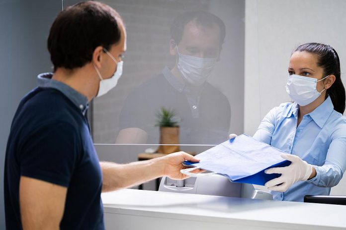 Shopper in a face mask accepting a purchase from a cashier in a face mask