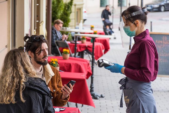 A masked waitress takes an order from customers at a restaurant in Lithuania during the COVID-19 pandemic. The Ontario government is considering a regional approach to reopening the province during the pandemic, in which restrictions would be loosened sooner in regions such as Peterborough that have low rates of COVID-19 cases. (Photo: Michele Ursi)