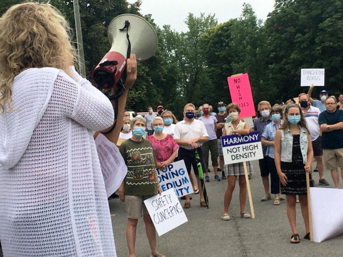 Adrienne Abrahamse addresses a large crowd that turned out Thursday night (July 16) in the parking lot of Thomas A. Stewart Secondary School in Peterborough for a rally against the proposed rezoning of land at Armour Road and Cunningham Boulevard that will allow a seven-storey apartment building to be constructed. The rezoning recommendation, changing the land use designation from commercial to high density residential, was carried in committee on July 6 but will go to full council for a final vote July 27. (Photo: Paul Rellinger / kawarthaNOW.com)