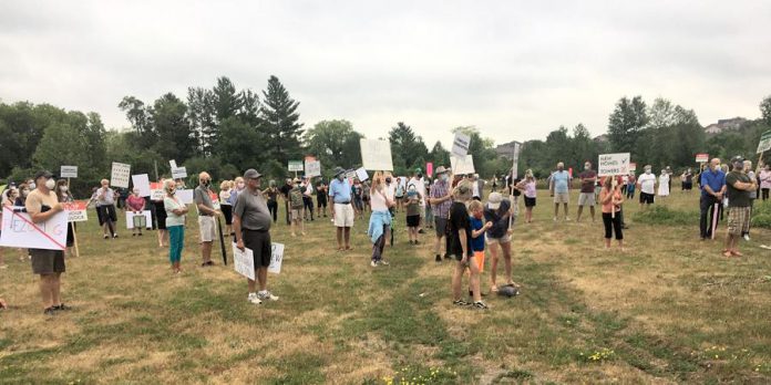  A large crowd gathered Thursday night (July 16) at the site of a proposed seven-storey apartment building at Armour Road and Cunningham Boulevard to rally against the project, citing increased traffic and flooding concerns, and with no stores within walking distance of the neighbourhood, the pending loss of the site's commercial use designation.  (Photo: Paul Rellinger / kawarthaNOW.com)