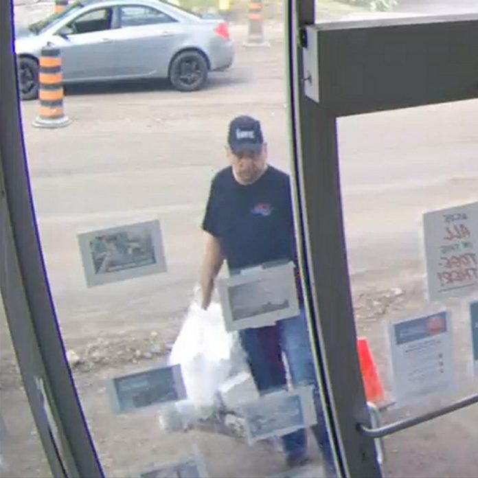 Surveillance footage shows a man who dumped two bags of garbage inside a Lindsay office on July 23, 2020. He was driving the grey car shown in the background. (Police-supplied photo)