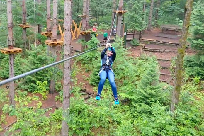 kawarthaNOW writer Paula Kehoe rides the zipline at Treetop Trekking in the Ganaraska Forest near Port Hope in 2017. Guests can will see changes at Treetop Trekking parks this year due to COVID-19, including fewer people in the area at one time, staff wearing personal protective equipment (PPE), hand sanitizer being readily available, and augmented cleaning procedures. (Screenshot)