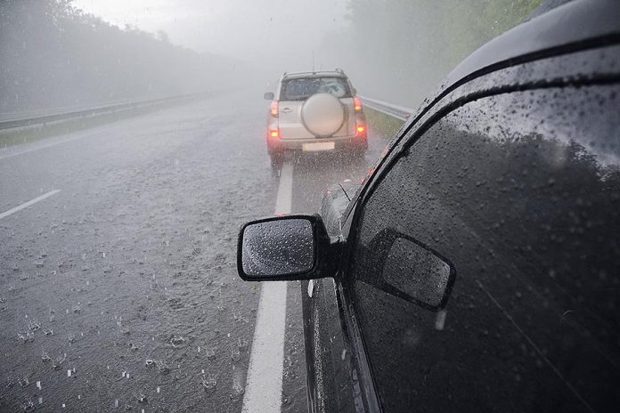 Two cars on a highway in a thunderstorm with hail. (Stock photo)
