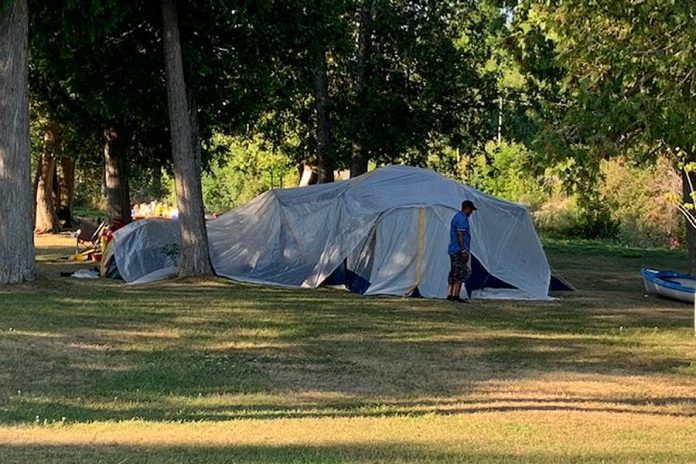 A kawarthaNOW.com reader who wishes to remain anonymous submitted this photo on August 1, 2020 of a large tent with about 30 people along River Road between Peterborough and Lakefield. Camping on Parks Canada land in this area is prohibited, and there are no public washrooms. (Supplied photo)