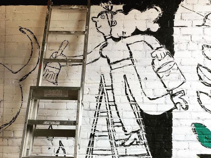 Artist Kathryn Durst's whimsical self-reference as she paints the other wall of the Commerce Building alleyway in downtown Peterborough. The second half of her mural will be available for viewing during the First Friday art crawl on October 2, 2020. (Photo: First Friday Peterborough)