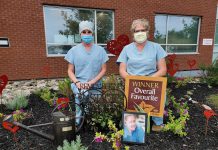 Theresa Connell and Marlene Dawson of Ross Memorial Hospital in Lindsay, two colleagues of late emergency department nurse Stacie Vokins, stand in the garden they dedicated to the memory of Vokins (shown in the picture frame), a 20-year employee of the hospital who passed away in November 2019. The garden, which includes heart sculptures by local artist Christina Handley, won the hospital's annual "Garden Cup". (Photo courtesy of Ross Memorial Hospital)