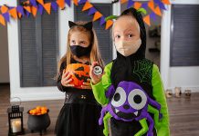 Two children wearing COVID-19 face coverings and Halloween costumes. (Stock photo)