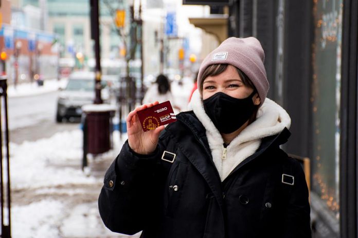 Shopper Deanna Henry displays a Downtown Dollars Gift Card now available for shopping in-store and on-line at participating businesses in downtown Peterborough. The card is available in $25, $50, $100, and $200 denominations. (Photo courtesy of Peterborough DBIA)