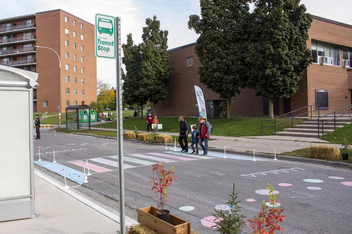 A family making use of the temporary crosswalk in Peterborough's Talwood neighbourhood on their way home from school. Adding colour to the crossing can signal to drivers that they should expect pedestrian activity, and it can also contribute to neighbourhood vibrancy and place-making. (Photo: Leif Einarson)