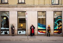 Former Toronto artist Julii McMillan (middle), who is now living in Peterborough, is one of the founders of the "Neighbourhood Love" public art campaign, launched this fall in Etobicoke when a family received hate mail after having a mural commissioned on their garage door. McMillan has joined with local artists Bethany LeBlonc (left), Dawn Pond, Brooklin Stormie, and Olivia Chessman and Toronto artists Julia Prajza and Bareket Kezwer (right) to paint six window murals in downtown Peterborough as part of the "Love for the Boro" initiative, including this mural at the old Patch Store at Hunter and George. (Photo courtesy of Love for the Boro)