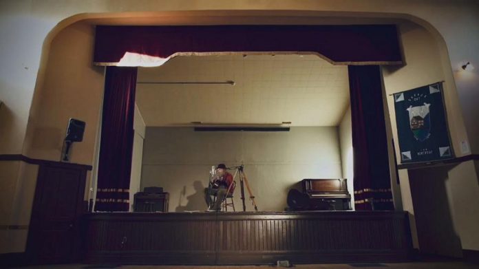 Neil Young performing 'Comes a Time' at an empty Coronation Hall in Omemee. He is making the film of his 2017 'Hometown' concert in Omemee, directed by his wife Daryl Hannah, available for free on his website during the  month of December. (Screenshot)