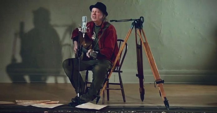 Neil Young performing 'Comes a Time' at an empty Coronation Hall in Omemee. He is making the film of his 2017 'Hometown' concert in Omemee, directed by his wife Daryl Hannah, available for free on his website during the month of December. (Screenshot)