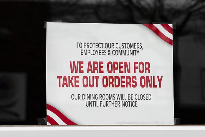 A sign in a restaurant window indicating it is open for take-out only due to the COVID-19 pandemic. (Stock photo)