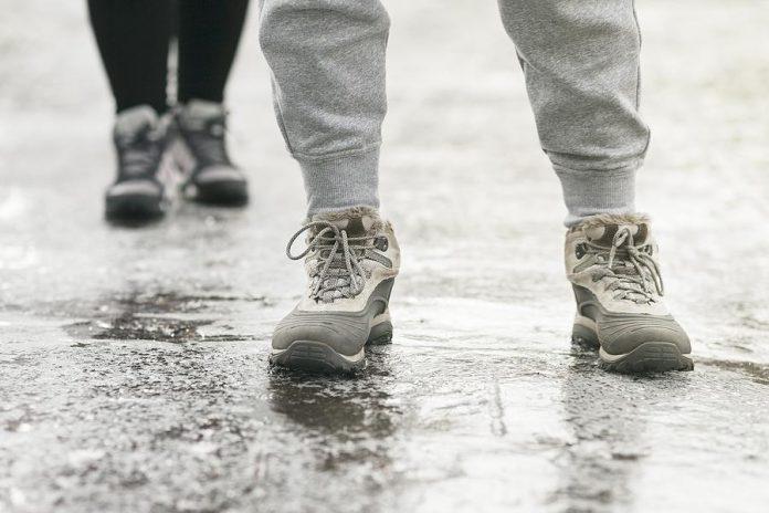 Two pedestrians walking on an icy surface. (Stock photo)