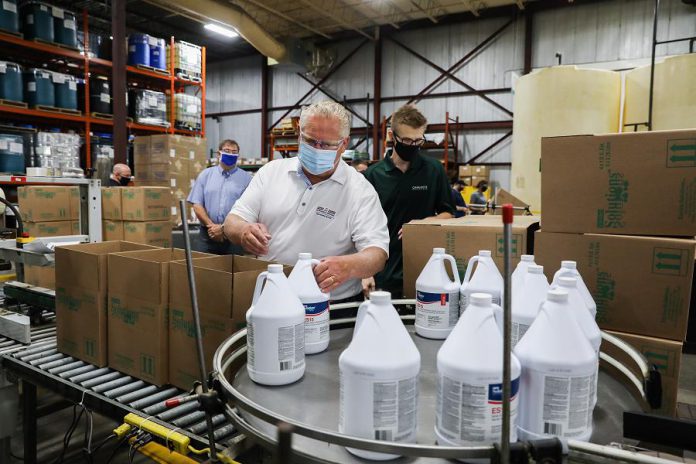 Premier Doug Ford packing bottles of disinfectant into boxes during a tour of Charlotte Products in Peterborough on July 30, 2020. Charlotte Products has ramped up production of its cleaning products during the pandemic and is facing a shortage of bottles for its products. Along with a $1 million provincial investment, Peterborough's Merit Precision is investing $1.3 million for an expansion that will allow it to supply bottles to Charlotte Products. (Photo: Government of Ontario)