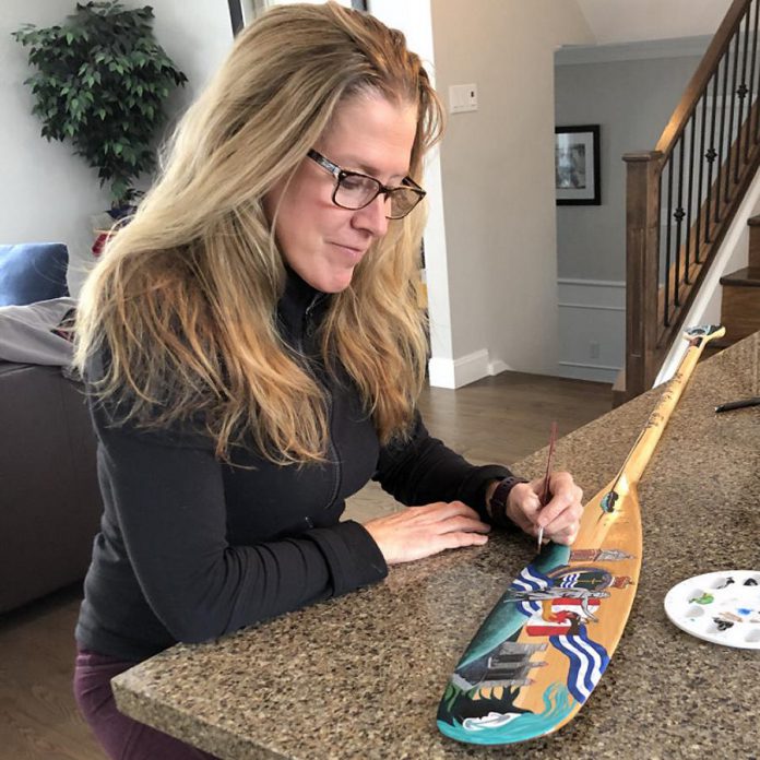 Retired police officer Kelleigh Traynor-Hartnett paints a paddle on behalf of the Peterborough Police Service for the Painted Paddle art exhibit, which features 20 canoe paddles painted by volunteer artists. The self-guided exhibit will be on display at various locations throughout downtown Peterborough during February. (Photo courtesy of Peterborough DBIA)