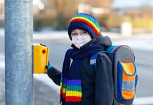 A child going to school while wearing a mask at a crosswalk. (Stock photo)