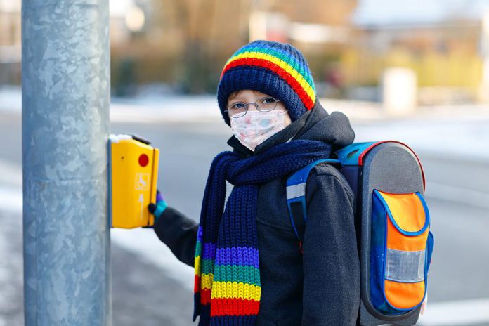 A child going to school while wearing a mask at a crosswalk. (Stock photo)