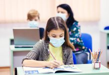 A young female student wearing a mask in a classroom. (Stock photo)