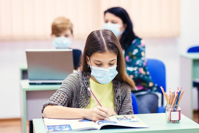 A young female student wearing a mask in a classroom. (Stock photo)