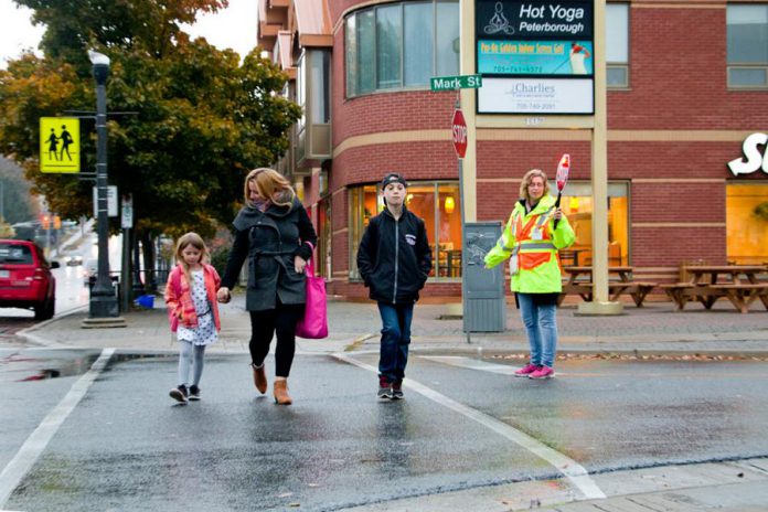 A family crosses Mark Street at Hunter Street in Peterborough's East City, a neighbourhood whose residents have access to almost everything they need within a 15-minute walk, including elementary schools, a grocery store, a drug store, restaurants, playgrounds and parks, public transit, and more. (Photo courtesy of GreenUP)