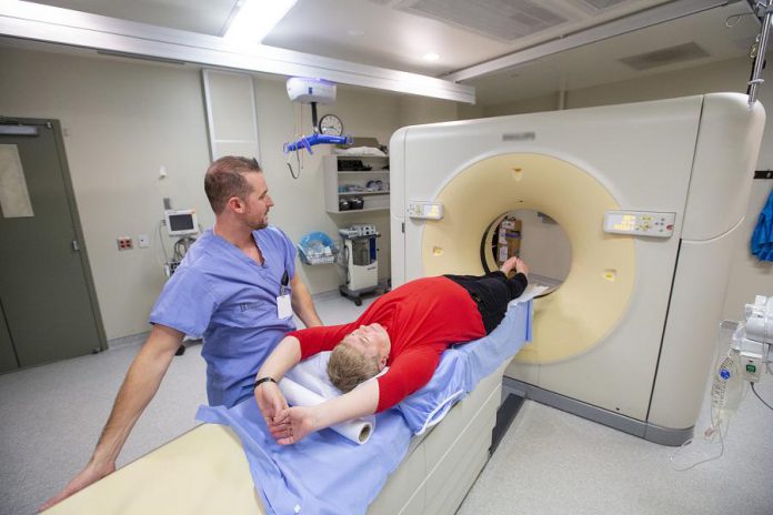 In this photo taken prior to the pandemic and universal masking protocols, a medical radiation technologist and volunteer demonstrate the current CT scanner technology at Peterborough Regional Health Centre. CT scans help doctors diagnose or rule out issues such as brain bleeds, blockages in arteries, bone fractures, appendicitis, kidney stones, and pneumonia, among many others. (Photo: Michael Hurcomb)