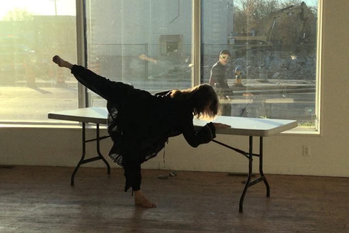 A passerby watches Public Energy's 2020-2021 Artist in Residence Irèni Stamou as the choregographer and dance artist completes movement research in a rehearsal space at Artspace Peterborough. Public Energy is seeking applications from artists for its 2021-2022 Local Artist in Residence Program. (Photo courtesy of Public Energy)