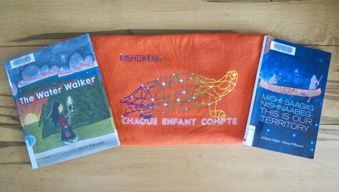 "The Water Walker" by Joanne Robertson and "Michi Saagig Nishnaabeg" by Gidigaa Migizi, with a Chaque Enfant Compte t-shirt by Nish Tees. According to the Nish Tees website, the "Mshiikenh (Turtle) is part of our 7 grandfather teachings. It is used to teach us about truth (debwewin)." (Photo: Leif Einarson) 