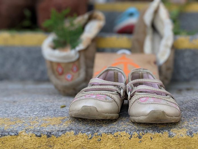 A pair of children's shoes on the steps of Peterborough City Hall, part of a community memorial created in response to last week's discovery of the remains of 215 Indigenous children buried at the former Kamloops Indian Residential School in British Columbia. (Photo: Bruce Head / kawarthaNOW)