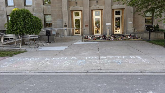 "Every Child Matters" is written in chalk in front of the memorial on the steps of Peterborough City Hall. (Photo: Bruce Head / kawarthaNOW)