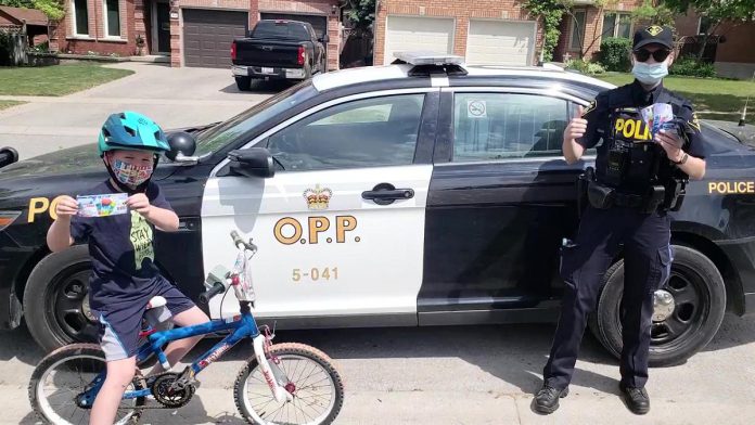 A child with a coupon for a free 'Froster' at a local Circle K convenience store from a local OPP officer. Under the OPP's positive ticketing program, kids will be rewarded this summer for practising personal safety (such as by wearing a bicycle helmet), performing good deeds, and more. (Photo: OPP)