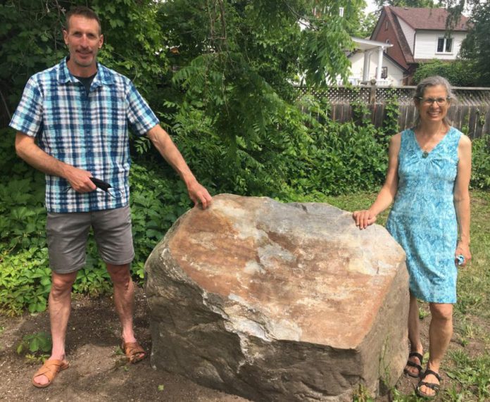 Ashburnham Ale House owner Scott Wood and City of Peterborough transportation demand management planner Sue Sauve stand by the boulder that will soon be home to an embossed metal plaque that will recognize the contributors to the $60,000 cost of lighting the Rotary Greenway Trail from Hunter Street East to Douro Street in Peterborough's East City. (Photo: Paul Rellinger / kawarthaNOW)