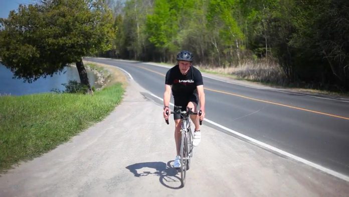Peterborough musician and puppeteer Glen Caradus training for his 350-kilometre bike ride on August 7, 2021 to raise awareness of climate change and funds for Peterborough GreenUP's climate-related programming. (Screenshot by kawarthaNOW from promotional video by Jeremy Kelly)