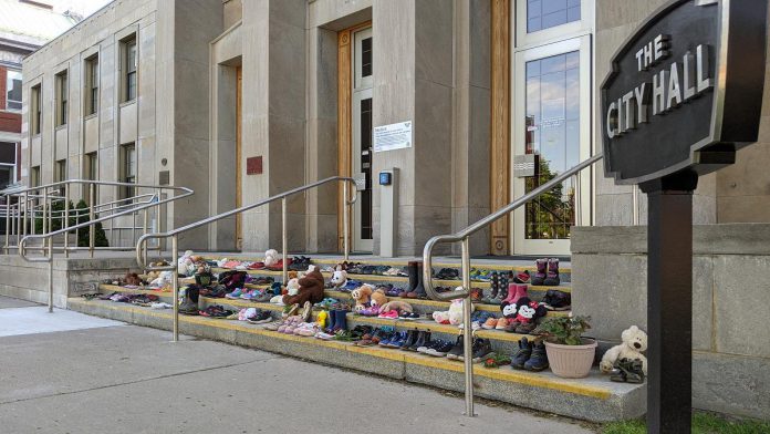 After the remains were discovered of 215 Indigenous children buried at the former Kamloops Indian Residential School in British Columbia in May 2021, the Indigenous community of Nogojiwanong-Peterborough created a memorial on the steps of Peterborough City Hall. On August 3, the 215th day of 2021, members of Curve Lake and Hiawatha First Nations will hold a day of mourning in Nogojiwanong-Peterborough to remember and recognize all Indigenous children whose lives were lost to Canada's residential school system. (Photo: Bruce Head / kawarthaNOW)