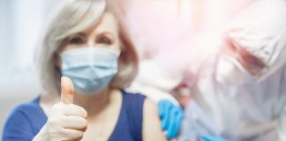 A woman giving a thumbs up as she receives a vaccination. (Stock photo)