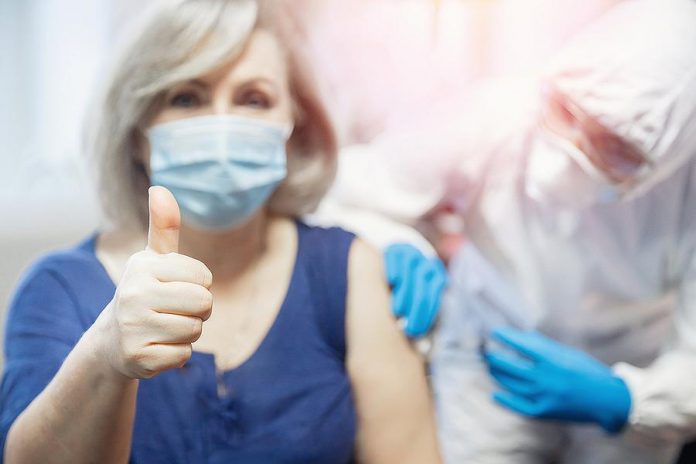 A woman giving a thumbs up as she receives a vaccination. (Stock photo)