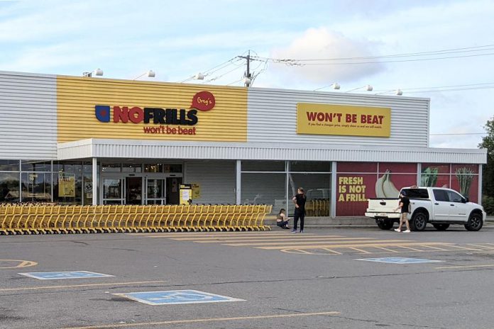 A line of shopping carts blocks the entrance at Greg's No Frills on George Street in downtown Peterborough, with employees on hand to advise perplexed customers the store is temporarily closed due to an early morning electrical fire on August 18, 2021. (Photo: Bruce Head/ kawarthaNOW)