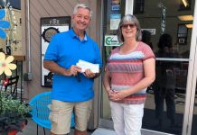 David McNab, who is leading an effort to bring 18-year-old Syrian refugee Rashid to Canada, accepts a $1,000 donation from Brenda Ibey, owner of The Avant-Garden Shop, for his fundraising campaign. Thanks to the generosity of Ibey and other business owners, along with individual donors from Peterborough and around the world, McNab has exceeded his goal by 50 per cent of raising $8,000 to cover the costs of supporting Rashid in Canada. (Photo: Clayton Ibey)