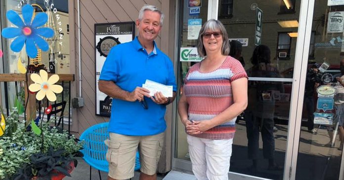 David McNab, who is leading an effort to bring 18-year-old Syrian refugee Rashid to Canada, accepts a $1,000 donation from Brenda Ibey, owner of The Avant-Garden Shop, for his fundraising campaign. Thanks to the generosity of Ibey and other business owners, along with individual donors from Peterborough and around the world, McNab has exceeded his goal by 50 per cent of raising $8,000 to cover the costs of supporting Rashid in Canada. (Photo: Clayton Ibey)