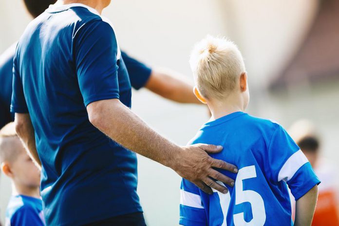 A coach supporting a young player during a soccer game. (Stock photo)