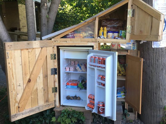 The new community fridge, currently installed in front of a private residence at 225 Dublin Street in downtown Nogojiwanong-Peterborough, includes a refrigerator for fresh food and a pantry for non-perishables, menstruation products, pet food, personal protective equipment, and more. (Photo courtesy of Community Fridge Ptbo)