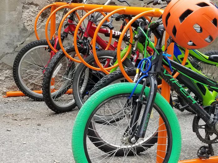 Many schools in Peterborough have front-wheel slot-style racks that are known to cause bike damage and are difficult to lock properly to. A bike rack should provide two points of contact for stability and proper locking. Ring-style bike racks allow two points of contact to properly lock a bike and allow for increased capacity. (Photo courtesy of GreenUP)