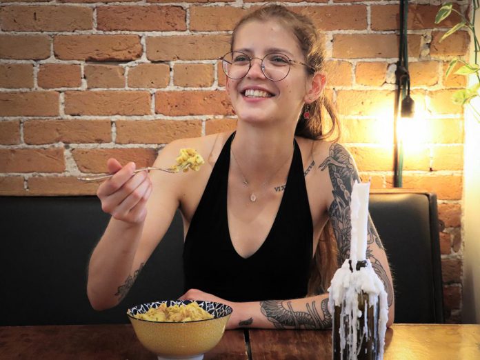 Lasair Wood, owner and operator of The Food Forest, one of 18 downtown Peterborough restaurants participating in the first-ever Mac + Cheese Festival during the month of October, digs into a bowl of  Vegan Mac. (Photo: Mac + Cheese Festival / Peterborough DBIA)