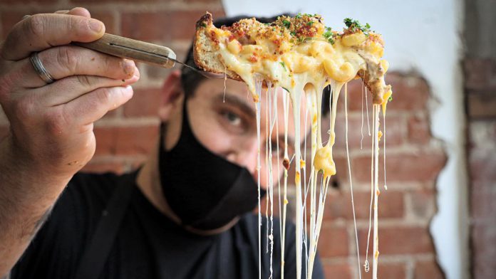 Taso Hatzianastasiou, owner and operator of Taso's Restaurant and Pizzeria, shows off a Chicago-style deep dish mac 'n' cheese. Taso is one of 18 downtown Peterborough restaurants participating in the first-ever Mac + Cheese Festival during October. (Photo: Peterborough Downtown Business Improvement Area)