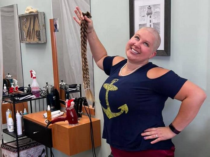 Omemee resident Britney Krzeminsk shows off her new look after having three 28-inch braids of her hair cut off on October 24, 2021 at Glenda's Place Hair Salon in Peterborough. After far exceeding her original fundraising goal by raising $4,100 for the Brain Tumour Foundation of Canada, Britney also had her head shaved. (Photo: Omemee Veterinary Hospital / Facebook)