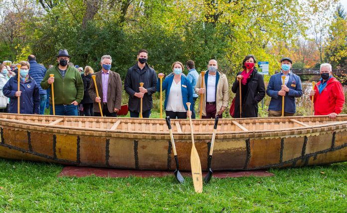 Some members of the integrated project delivery team for the design and build of the new museum at The Canadian Canoe Museum's construction commencement event on October 16, 2021 in front of a 26-foot long birchbark canoe built by Métis elder Marcel Labelle: Helen Batten of Basterfield & Associates Inc., Tim Coldwell of Chandos, Michael Harrington of JHG Consultants, Michael Gallant of Lett Architects, Carolyn Hyslop, Bill Lett of Lett Architects, Victoria Grant, Jeremy Ward, and  Scott Hunt of Chandos.  (Photo: FusionRiver Photography courtesy of The Canadian Canoe Museum)